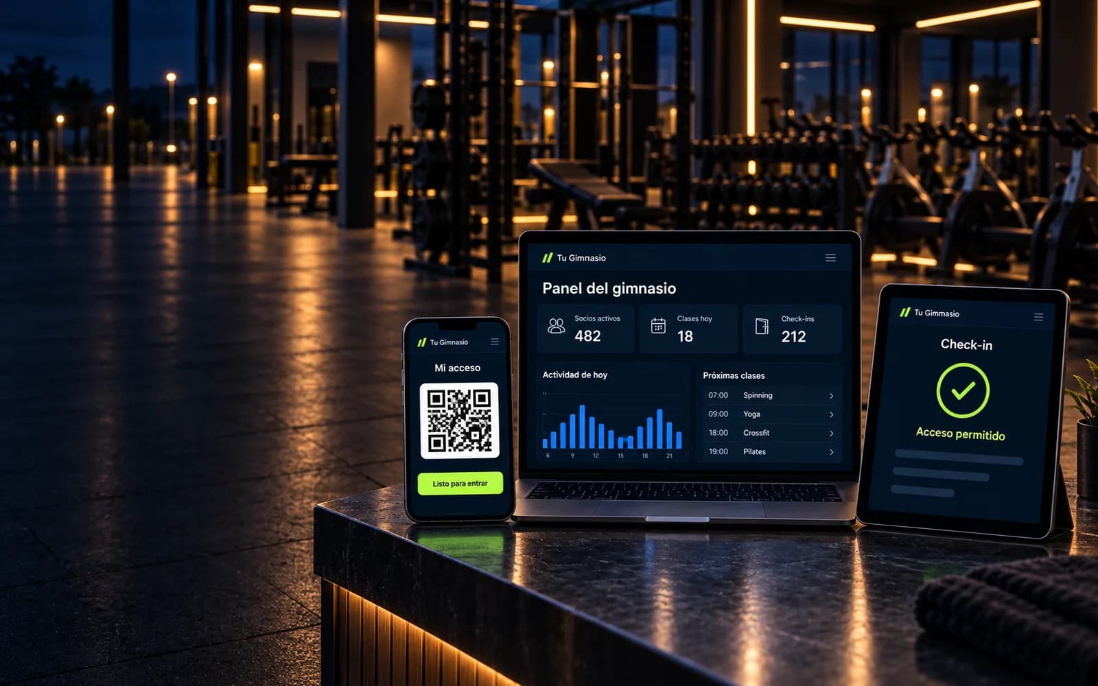 El sistema en tres pantallas sobre el mostrador de un gimnasio de noche: el panel del gimnasio en una laptop, el QR de acceso del socio en un teléfono y el check-in en una tableta