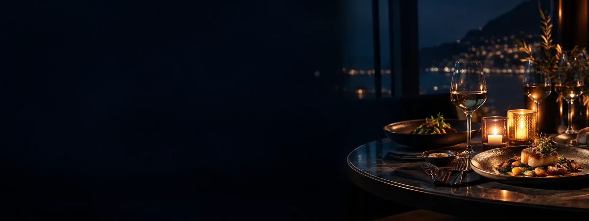 Una mesa de restaurante de noche con platillos, copas de vino y velas